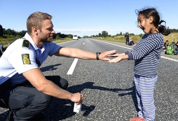 En photo : Un policier danois joue avec une jeune réfugiée syrienne